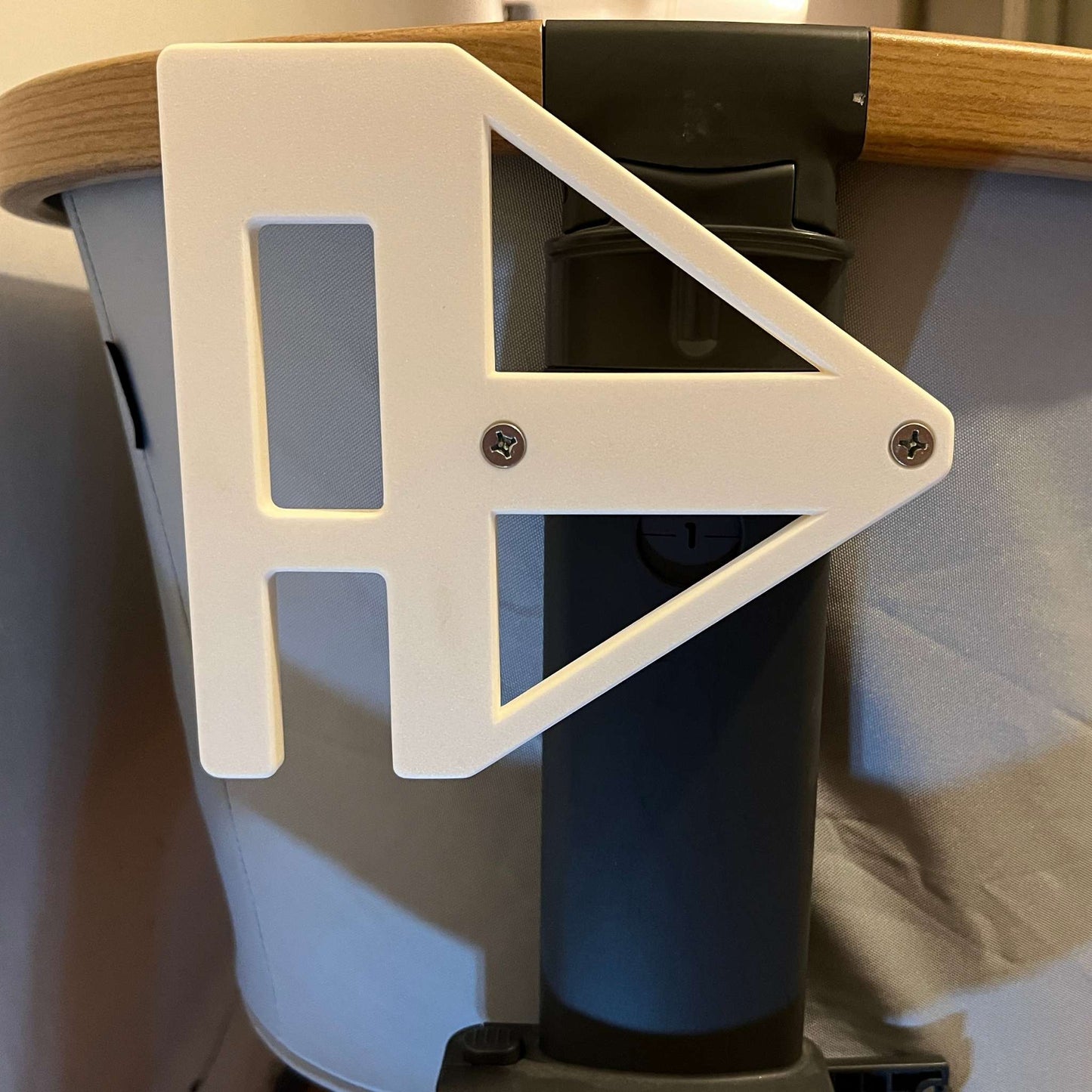 Zoomed in view Maxi-cosi_Iora white CribClamp attached to the bedside crib without a little dutch musical mobile. View of the Maxi-cosi co-sleeper and baby mobile attachment adapter bracket from the head side of the bedside cot