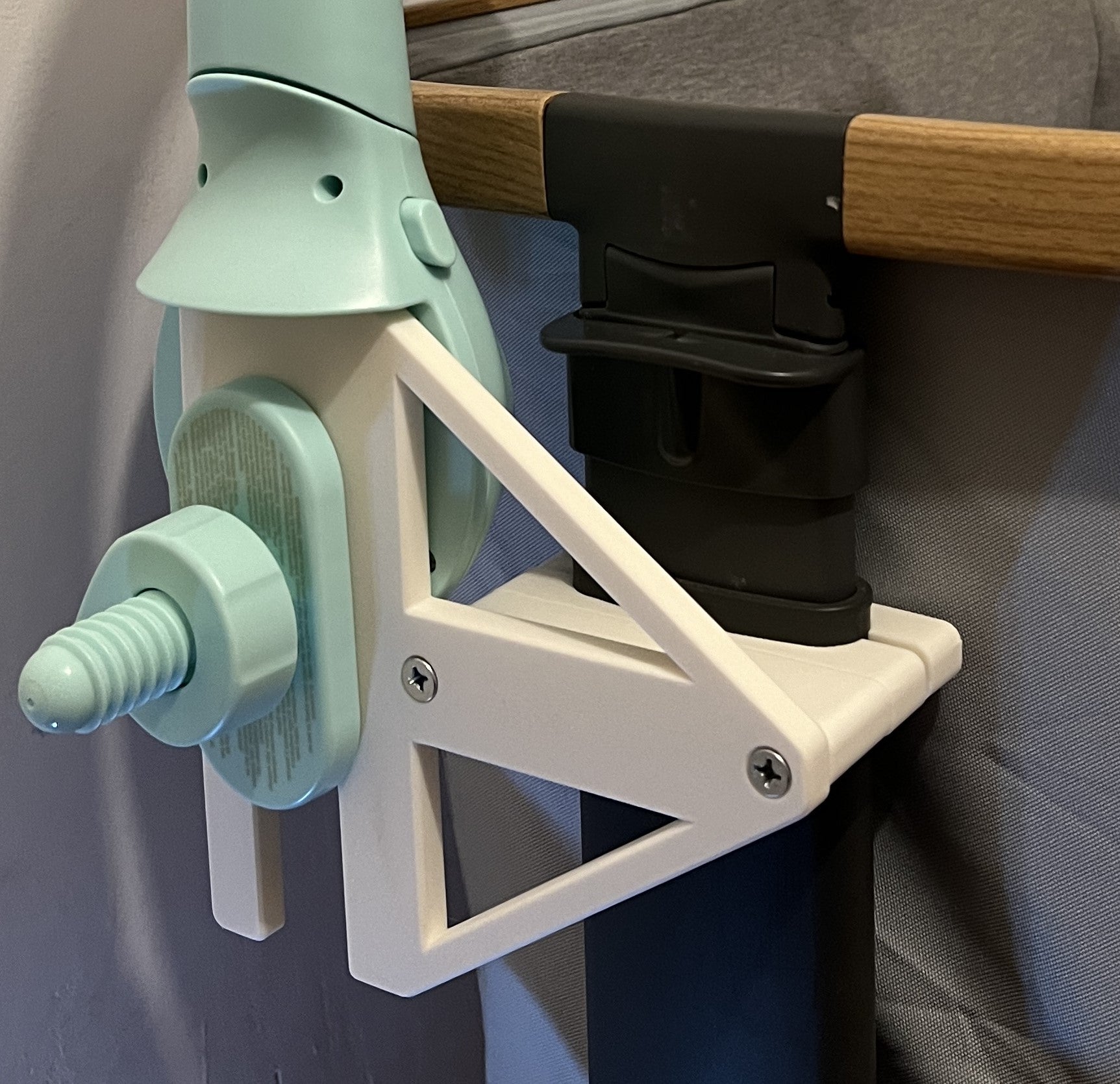 Zoomed in view Maxi-cosi_Iora white CribClamp attached to the bedside crib with an fantino 3 in 1 musical mobile. View of the Maxi-cosi co-sleeper and baby mobile attachment adapter bracket from the head side of the bedside cot